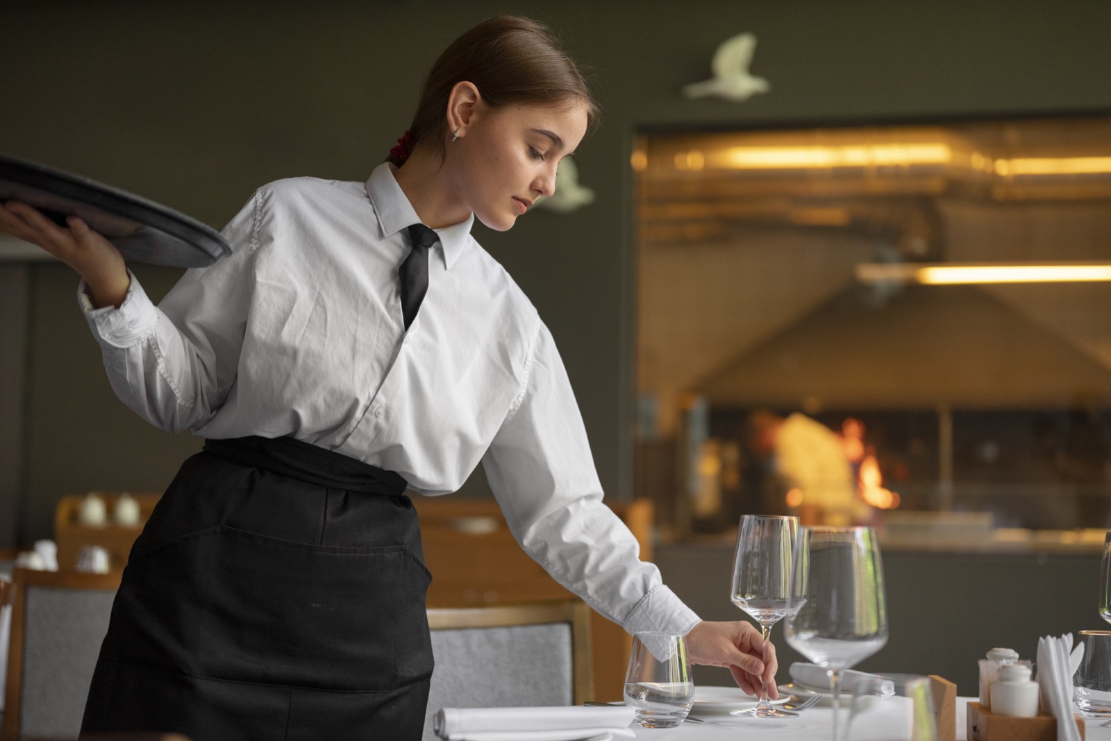 Servírka připravuje prostírání v restauraci
